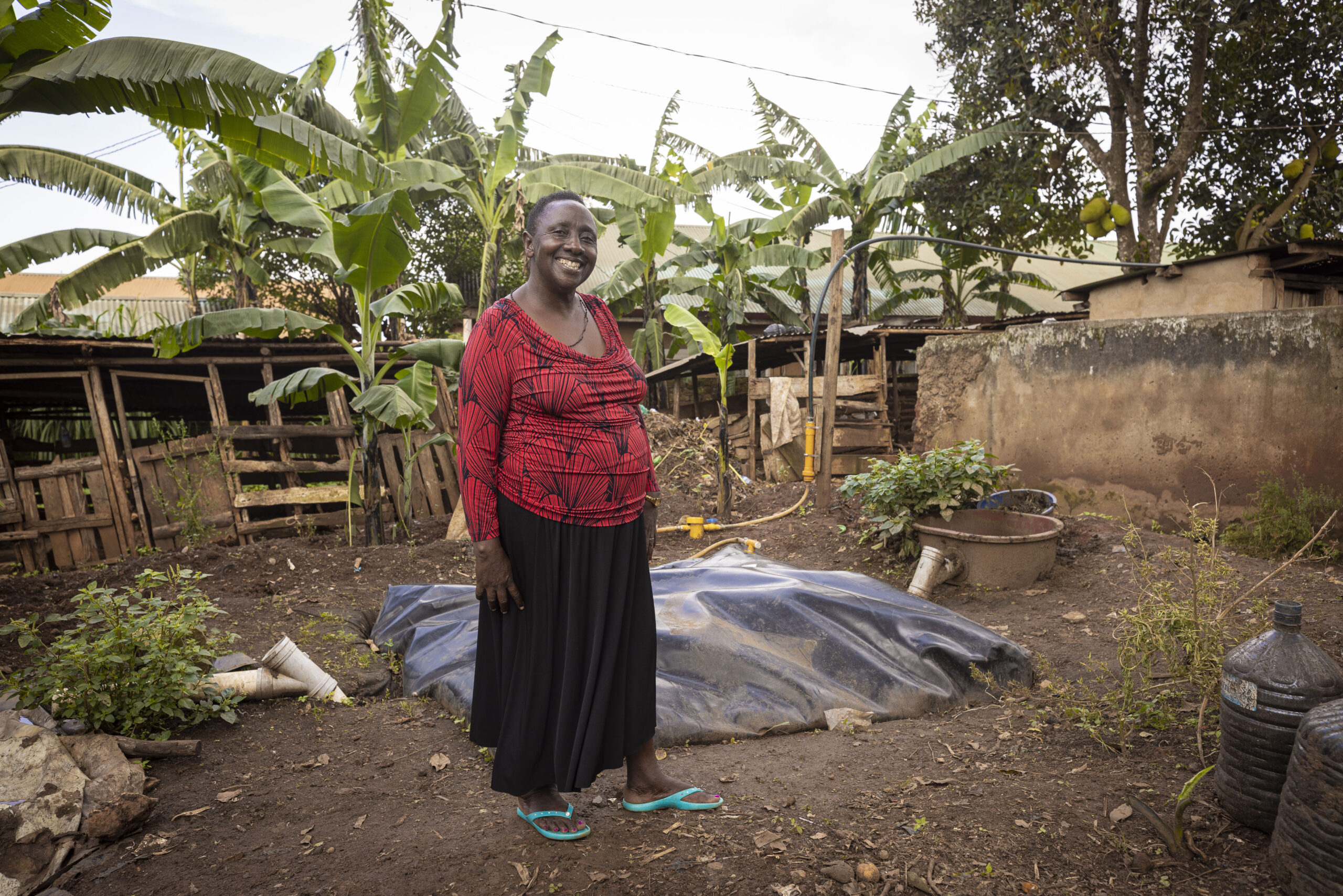 A Ugandan farmer stands near her digester which converts farm waste to fuel and cuts ghg emissions