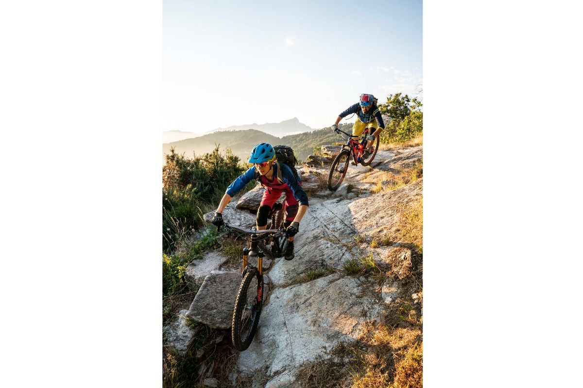 Two mountain bikers ride down a rocky cliff